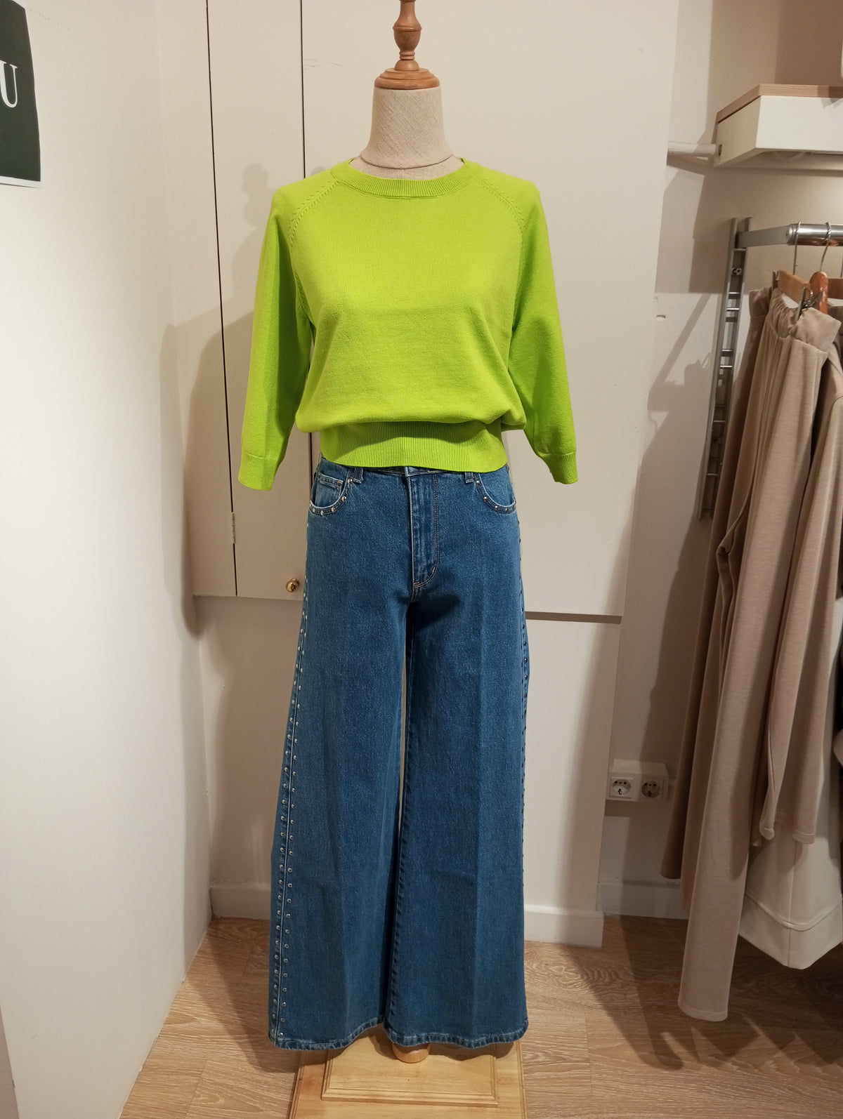 Jersey lima liso con tejanos anchos de tachuelas laterales, en maniquí