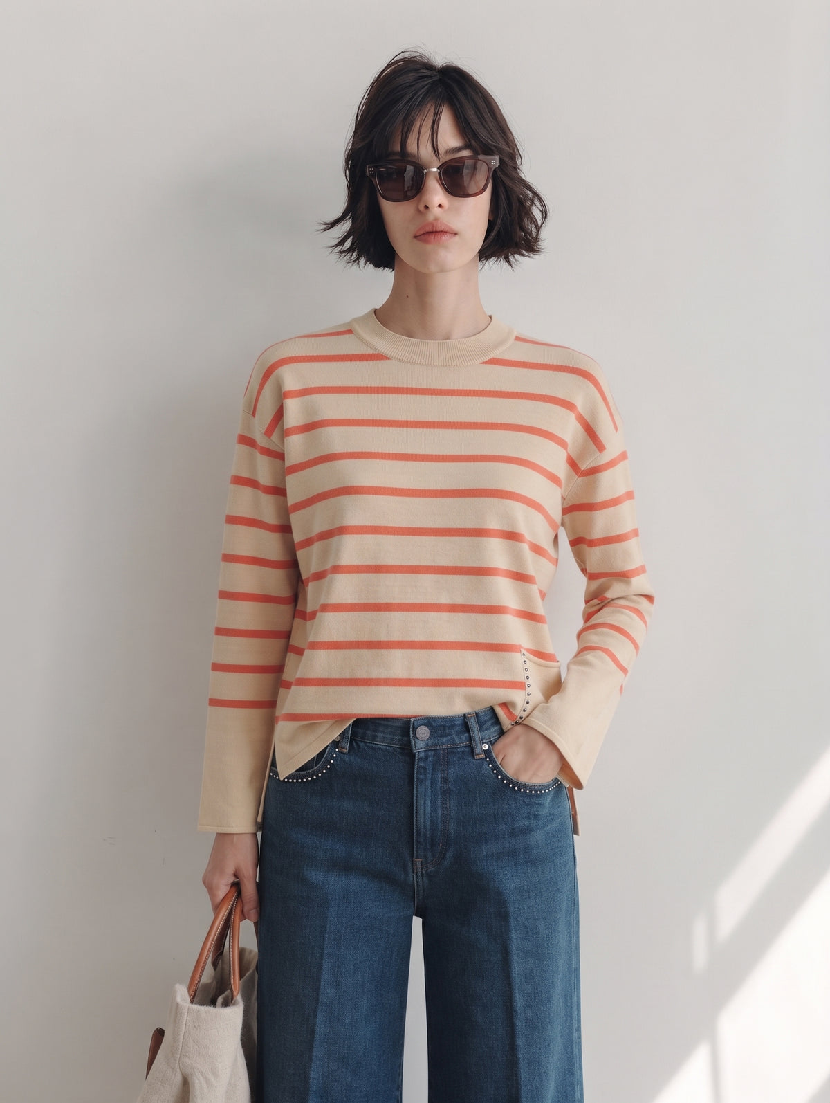 Jersey de rayas naranja para mujer con tejanos y bolso crudo, plano medio de frente
