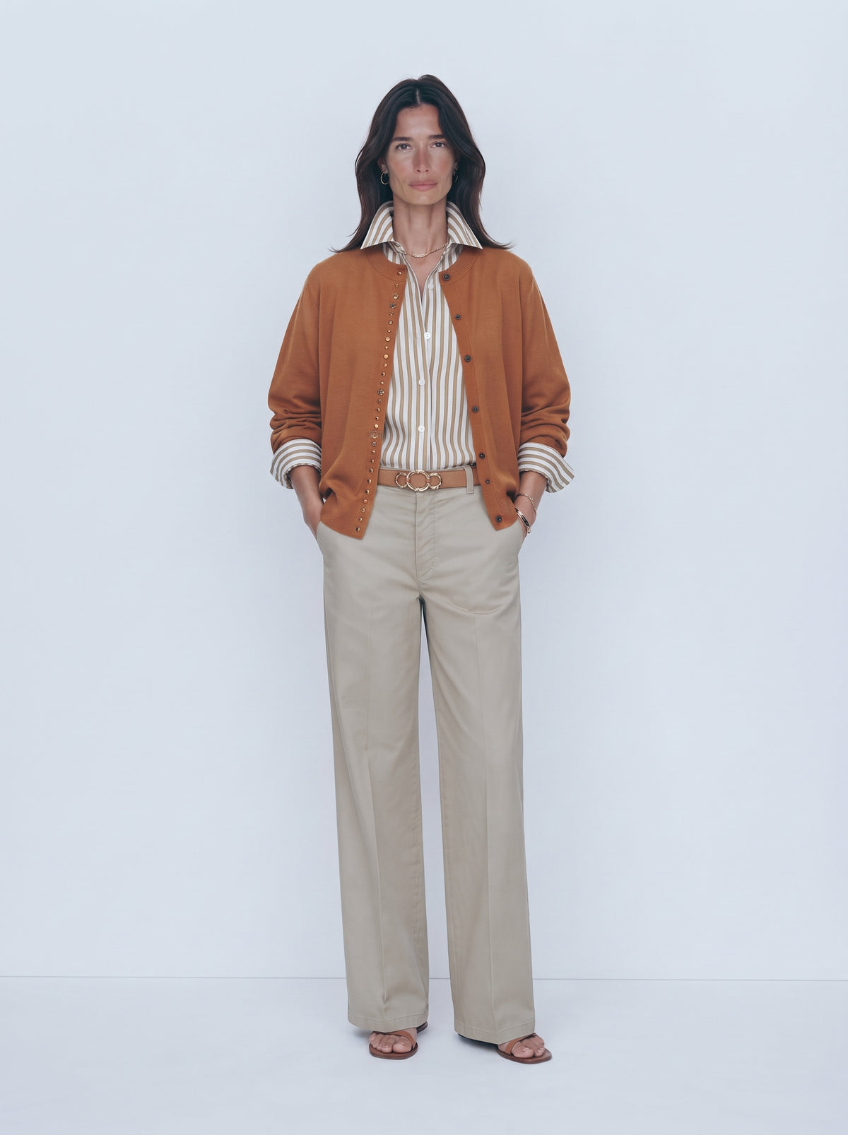 Rebeca mostaza con tachas metálicas, camisa de rayas y pantalón recto beige, cuerpo entero