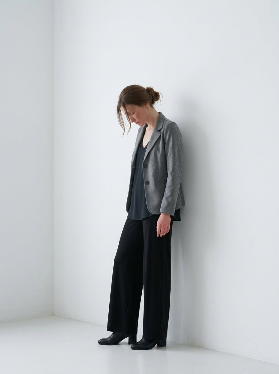 Americana básica gris con blusa y pantalón negros sobre fondo blanco