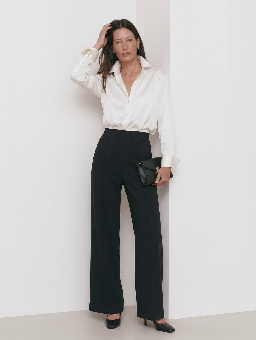 Pantalón recto negro con costuras frontales, camisa marfil y zapatos de tacón, cuerpo entero