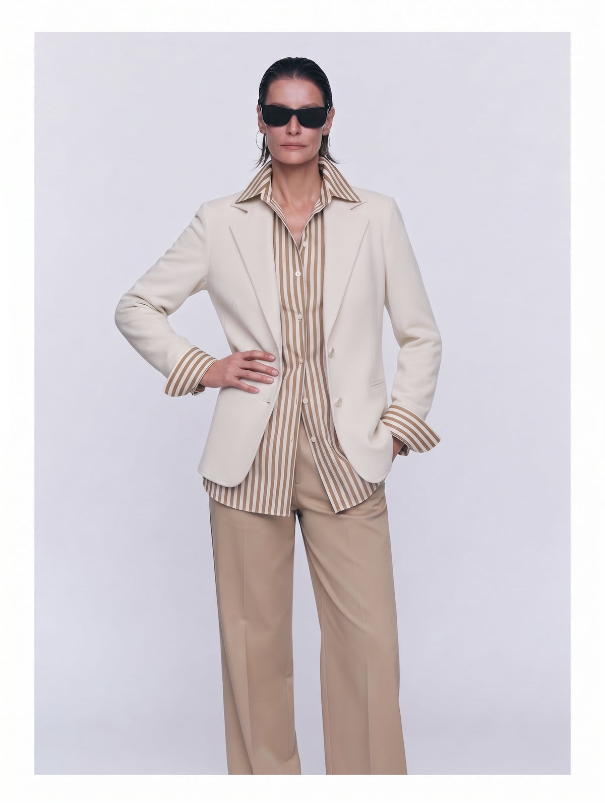 Pantalón recto beige con americana marfil abierta y camisa de rayas, plano medio