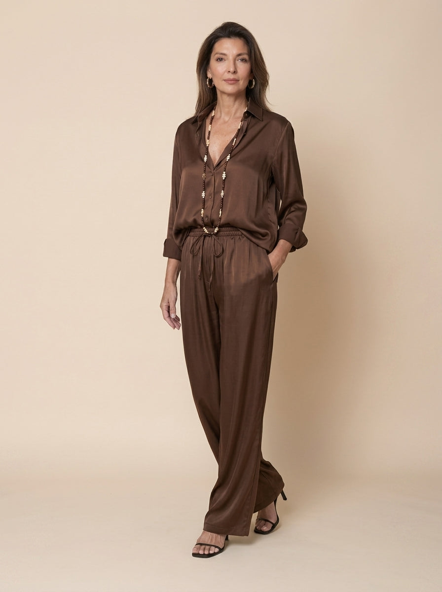 Camisa de raso marrón remangada con pantalón a juego y sandalias de tacón, cuerpo entero
