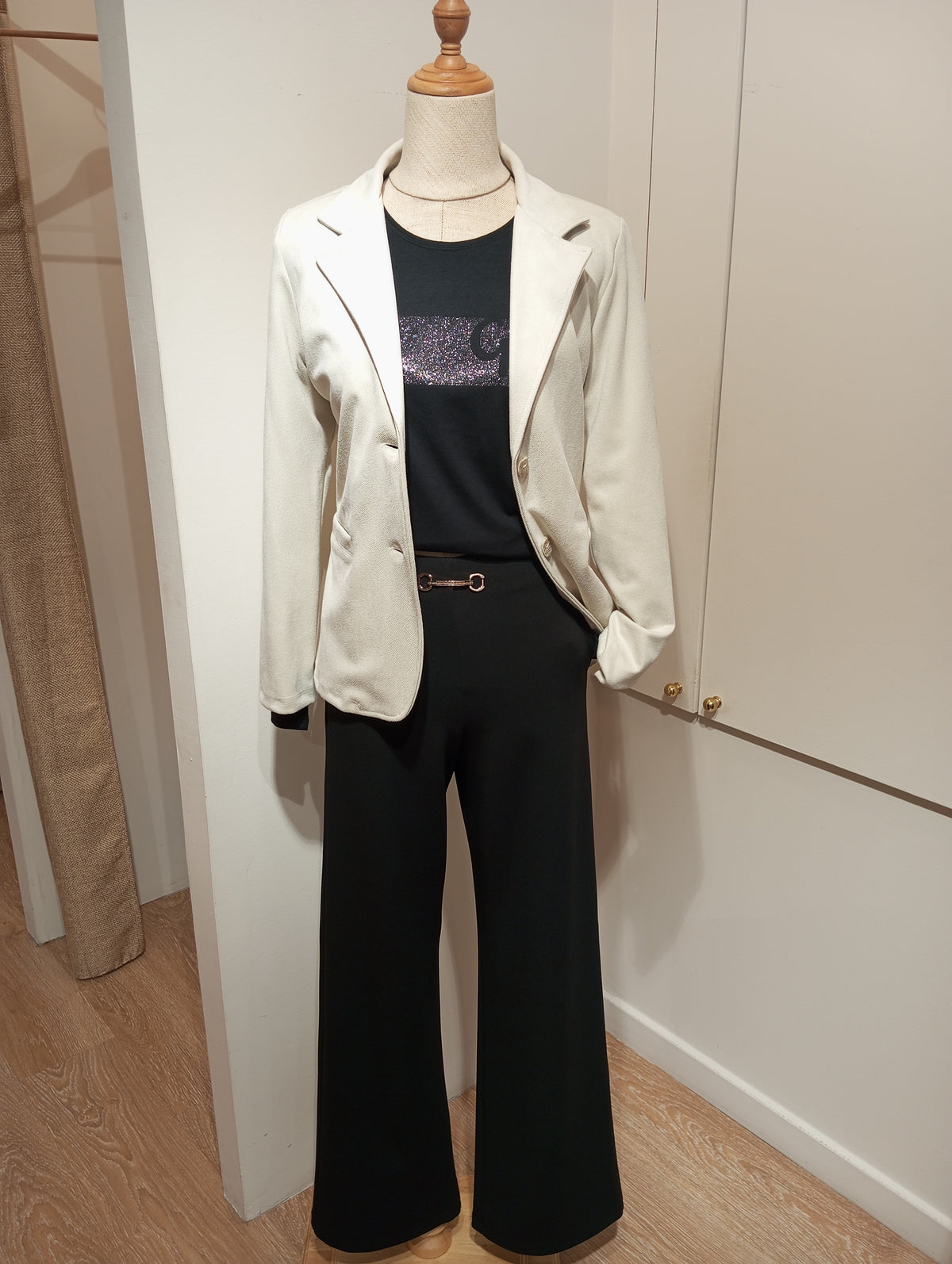 Camiseta negra de manga larga con logo brillante, americana crudo y pantalón negro en maniquí