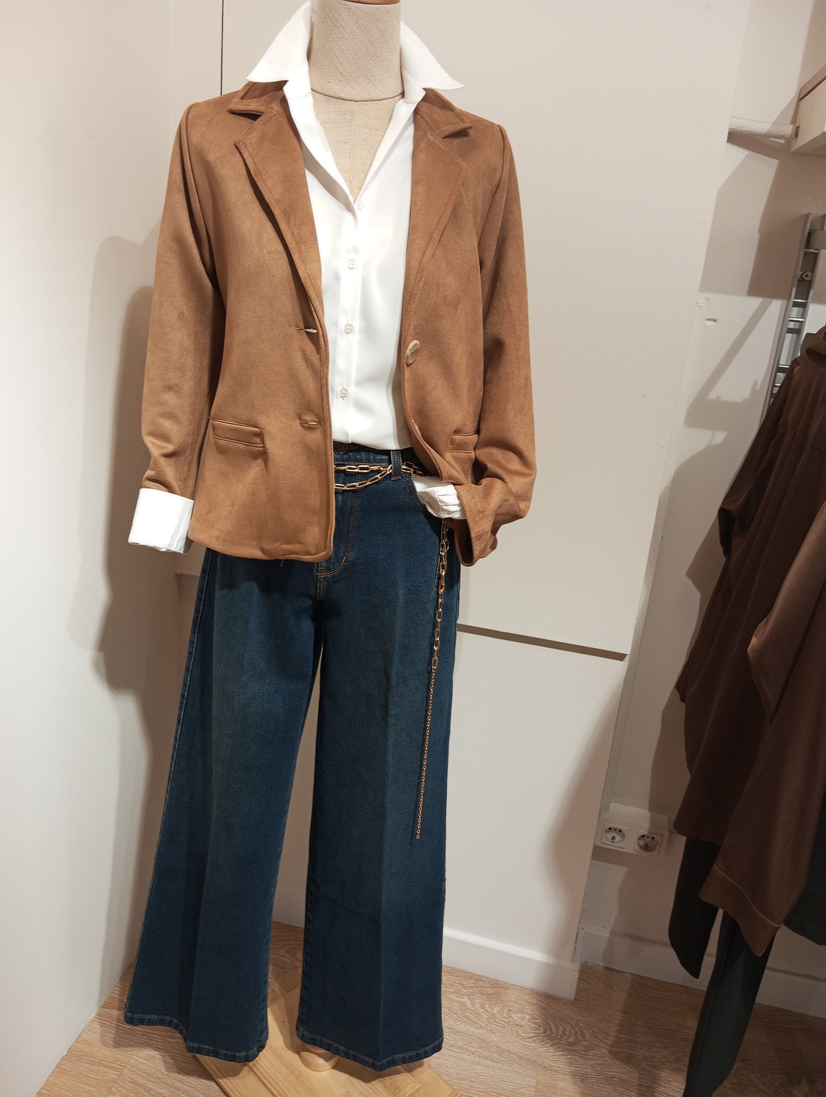 Americana de antelina camel con camisa blanca y vaquero ancho en maniquí