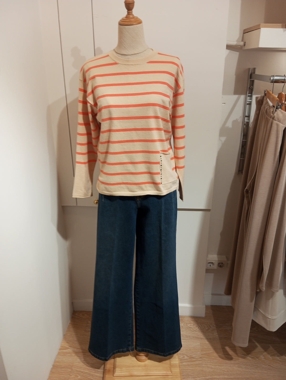Jersey de rayas naranja con bolsillo de tachuelas y tejanos anchos en maniquí