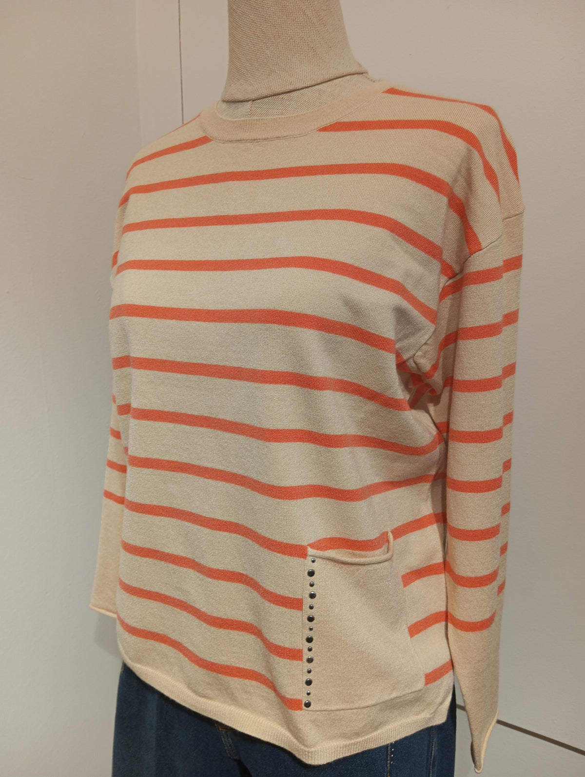 Jersey de rayas naranja en maniquí, detalle del bolsillo lateral con tachuelas